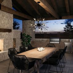 a dining room table with candles on it next to an outdoor fireplace and grill area