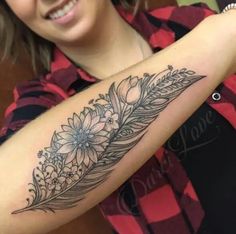 a woman with a flower and feather tattoo on her arm is smiling at the camera