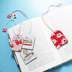 an open book with some tags hanging from it's sides on a blue table