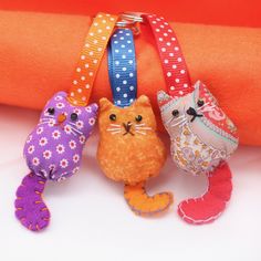 three small stuffed animals are hanging on a piece of orange fabric with polka dot ribbon