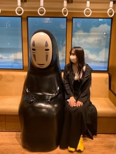 a woman wearing a face mask sitting on a bench next to a large black statue