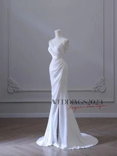 a white wedding dress on a mannequin in front of a wall and floor