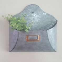 a potted plant sitting inside of a metal container on the wall next to a white wall