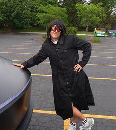 a woman standing next to a car in a parking lot