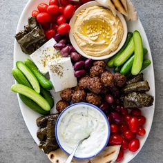 a platter filled with meat, vegetables and dip