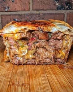 a sandwich cut in half on top of a wooden cutting board next to a brick wall