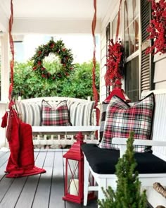 the porch is decorated for christmas with red and white decorations, wreaths and lanterns