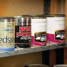 several cans of paint sitting on top of a metal shelf next to eachother