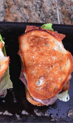 two halves of a sandwich sitting on top of a black tray next to each other