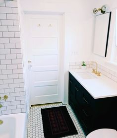 a white bathroom with black and white tile on the floor next to a bathtub