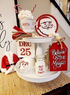 christmas decorations on a table in front of a stair case with santa's face