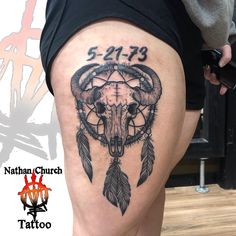 a woman's thigh with a bull skull and dream catcher tattoo on it