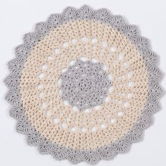 a crocheted doily is shown on a white surface with grey and beige circles