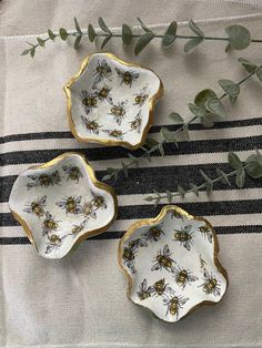 three honeybee dishes on a striped tablecloth with eucalyptus leaves in the foreground