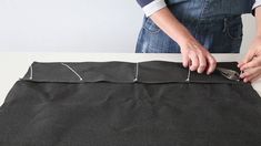 a person cutting fabric with scissors on top of a piece of black material that is sitting on a table