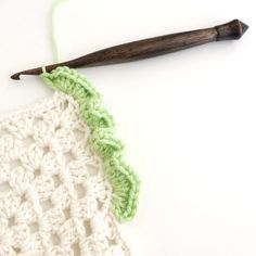 a crochet piece with a wooden knitting needle next to it