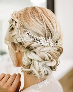 the back of a woman's head with braids and flowers in her hair