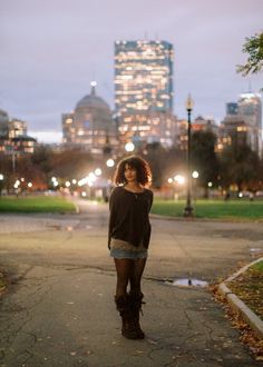 a woman standing on the sidewalk in front of a city skyline