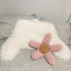 a pink and white stuffed animal laying on top of a bed next to a pillow