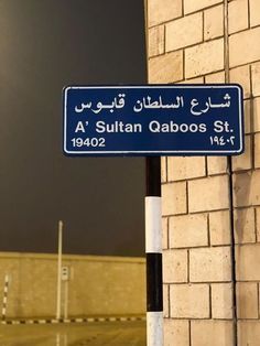 a blue street sign sitting on the side of a brick wall next to a building