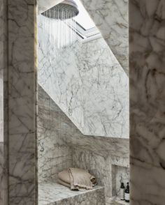 a bathroom with marble walls and flooring, including a skylight above the shower