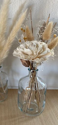 two glass vases with dried flowers in them