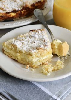 a piece of cake on a plate with a fork and orange juice in the background