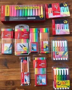 many different colored pencils in plastic containers on a wooden table with other pens and markers