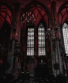 the interior of an old gothic church with stained glass windows and chandeliers hanging from the ceiling