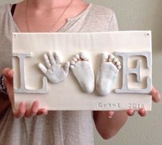 a woman holding up a sign with baby's handprints on it