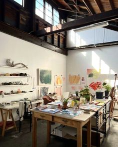 an artist's studio with lots of art work on the walls and desks