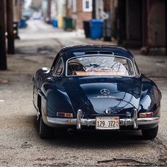 an old blue car is parked on the street