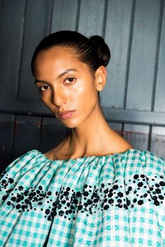 a woman in a green and white checkered top with black dots on her shoulders