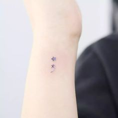 a small star tattoo on the left inner arm, with an arrow in the middle