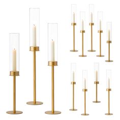 six tall candles with clear glass cylinders and gold bases