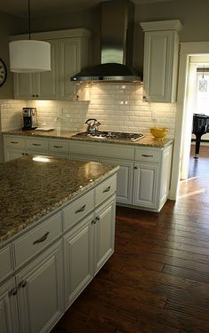 a large kitchen with white cabinets and granite counter tops, along with a piano in the background