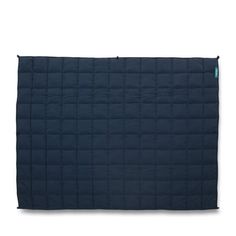 the navy blue quilted blanket is folded on top of a white surface and has a zipper