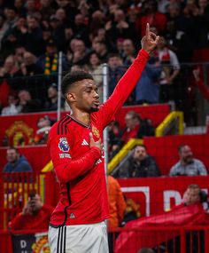 a soccer player holding his hand up in the air while standing next to a crowd