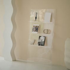 a white shelf with pictures and vases on it next to a wall mounted sculpture