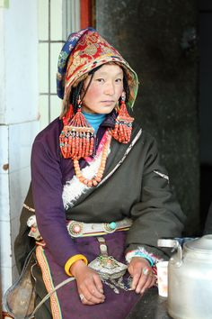 a woman sitting on top of a counter next to a pot