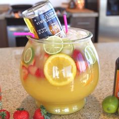 a pitcher filled with lemonade, strawberries and limes on top of a counter