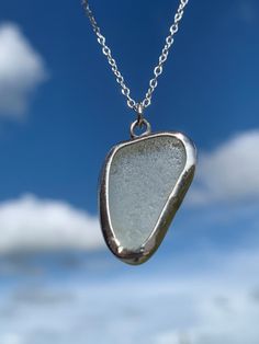 a close up of a glass pendant on a chain with sky in the back ground