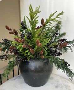 a potted plant sitting on top of a table covered in pine cones and berries