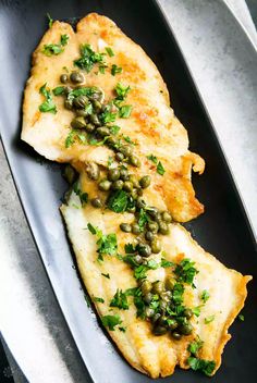 two pieces of fish covered in capers on a plate