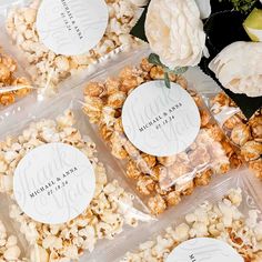 four plastic bags filled with popcorn sitting on top of a table next to white flowers