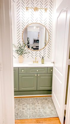 a bathroom with green cabinets and a mirror on the wall above the sink, along with a potted plant