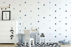 a child's room with black and white triangles on the wall next to a dresser