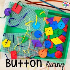 a green tray filled with colorful plastic buttons and string on top of a white table