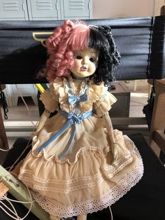 a doll sitting on top of a table next to a black box and some wires