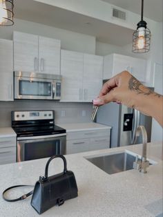 a woman's hand holding a small purse over a kitchen counter